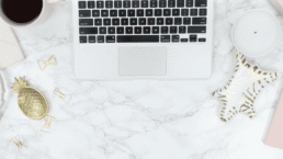 A laptop on a desk with pink and gold accents.